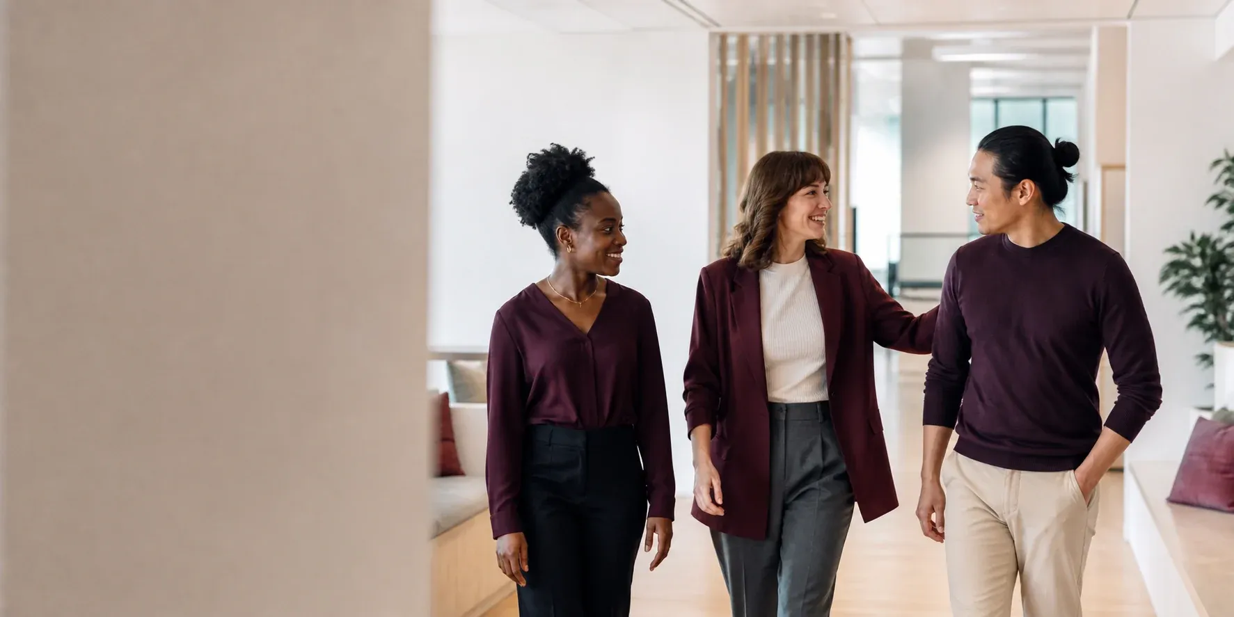 Three colleagues walking together through a bright workplace
